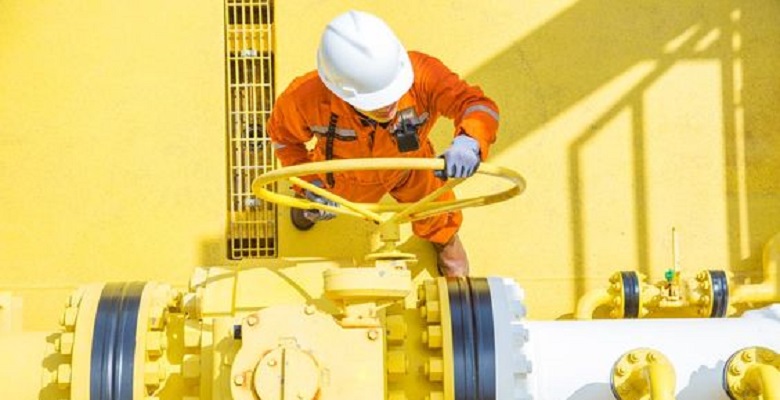 A worker controling the valve in yellow in the yellow background