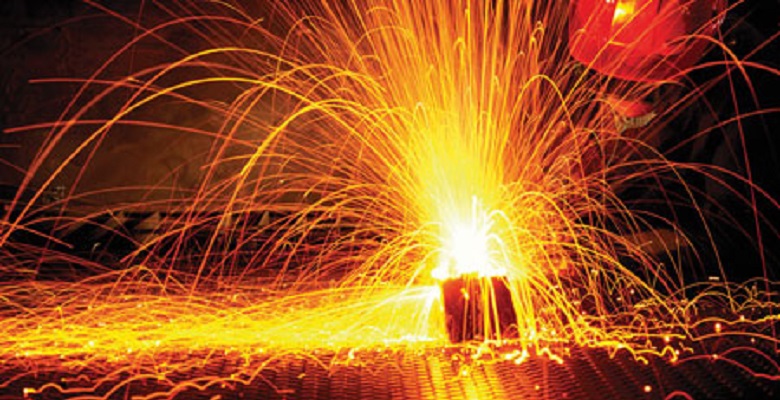 A sparkling scene where a worker is forging steel