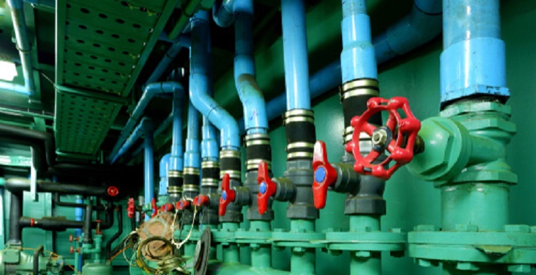 Focus on red gate valve on foreground with pipelines of main water pressure control in engine room area